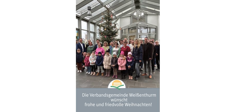 Bürgermeister Thomas Przybylla steht mit Mitarbeiterinnen und Mitarbeitern der VG und Kita-Kindern vor dem geschmückten Weihnachtsbaum. 