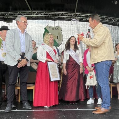 VG-Bürgermeister Thomas Przybylla überreicht der neuen Kirschblütenkönigin einen Regenschirm. Neben ihm steht die bisherige Kirschblütenkönigin, links der Stadtbürgermeister.