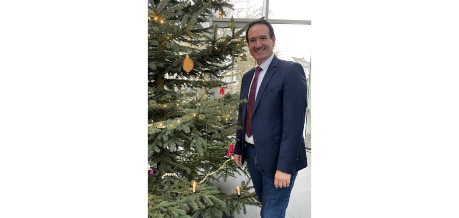 Bürgermeister Thoma Przybylla steht rechts neben dem geschmückten Weihnachtsbaum. 